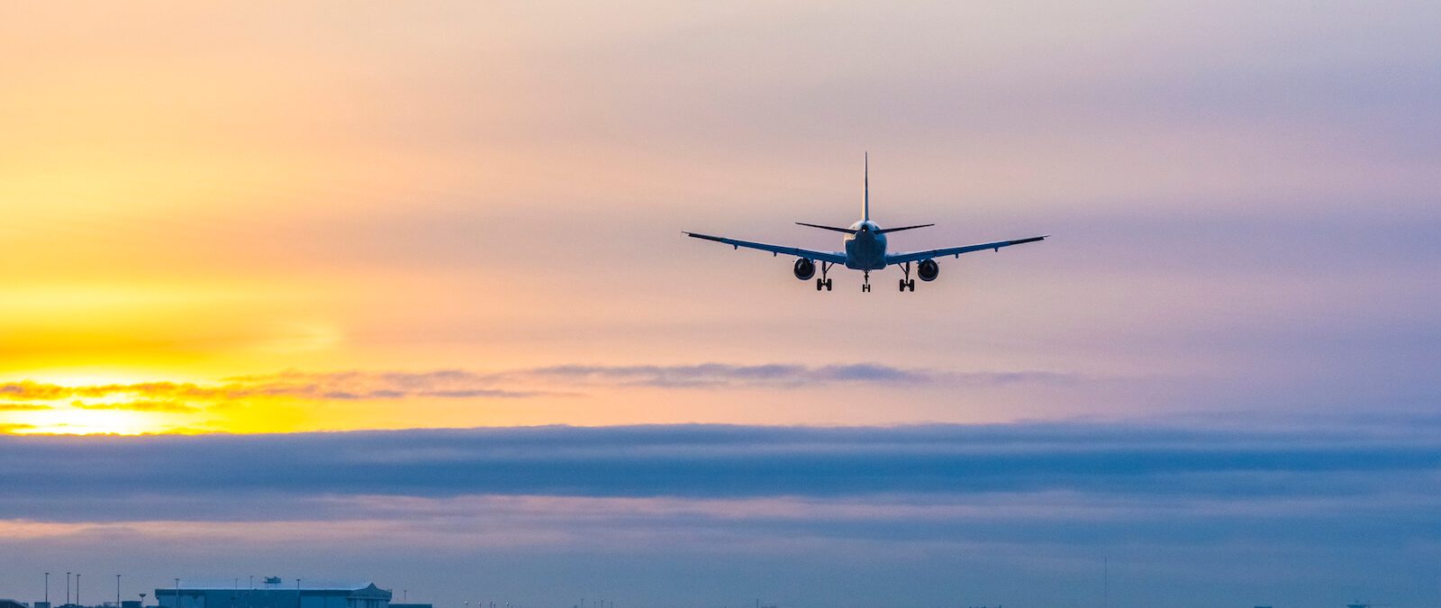 Flygplan i solnedgången på väg att landa.