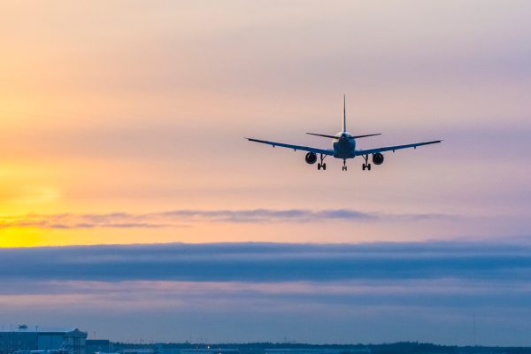 Flygplan i solnedgången på väg att landa.