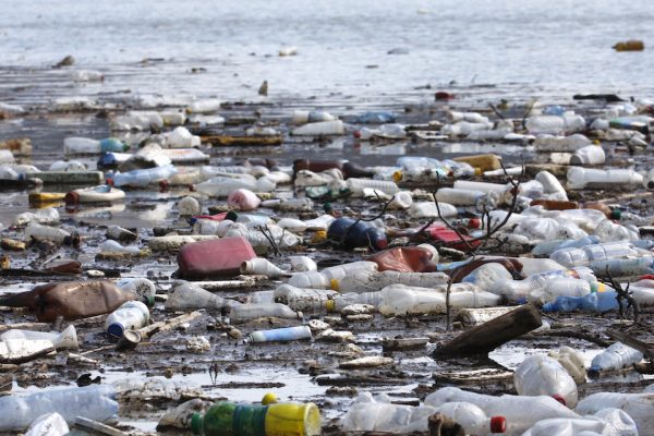 Plastskräp ligger på en strand vid havet.