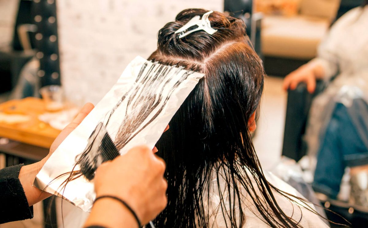 Kvinna får håret färgat på en frisersalong.