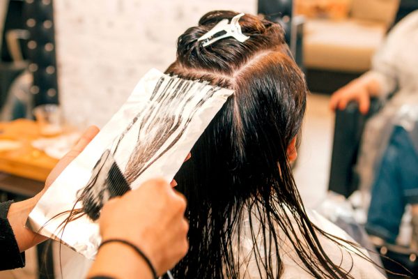 Kvinna får håret färgat på en frisersalong.