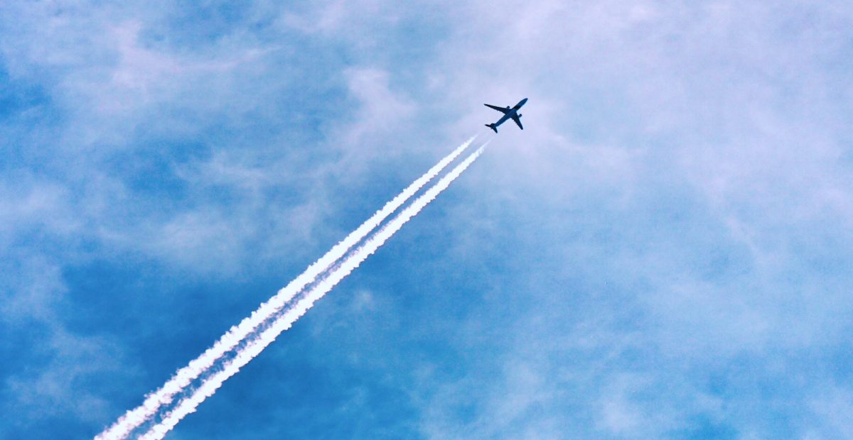 Flygplan med strimmor av vit ånga mot blå himmel.
