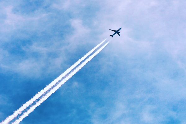 Flygplan med strimmor av vit ånga mot blå himmel.