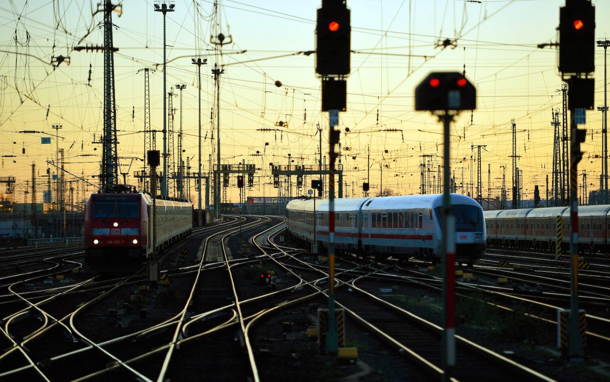 Järnvägsstation i skymning med rödljus och flera spår som går åt olika håll.