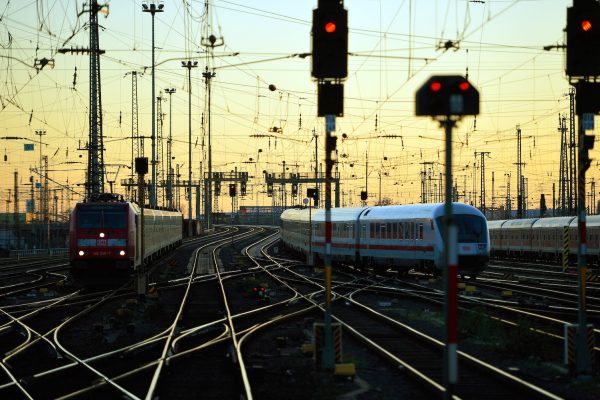 Järnvägsstation i skymning med rödljus och flera spår som går åt olika håll.