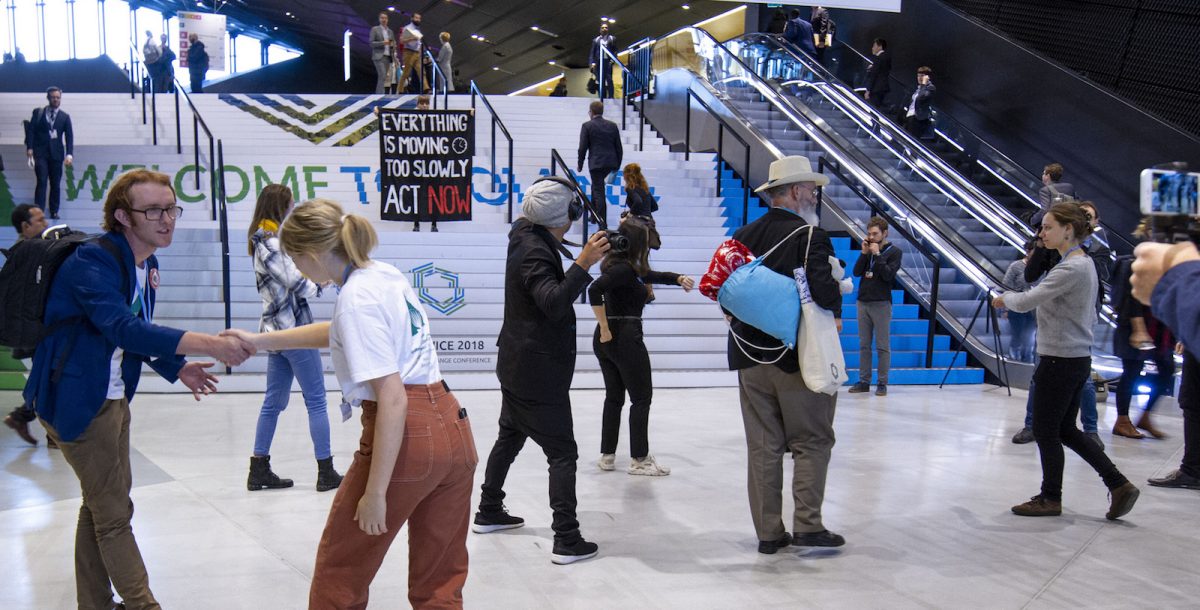 Människor protesterar i den stora hallen i konferenscentret där förhandlingarna pågår.