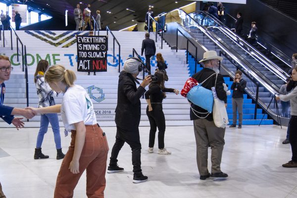 Människor protesterar i den stora hallen i konferenscentret där förhandlingarna pågår.