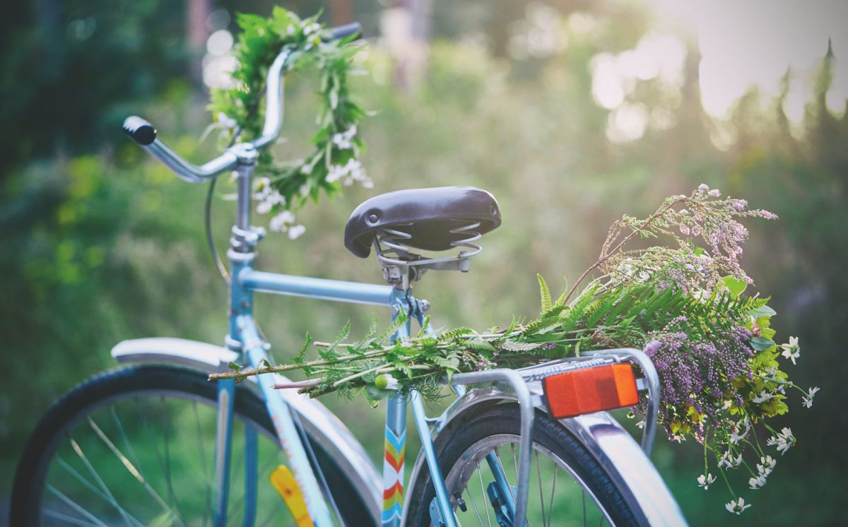 Blomsterkrans på styret till en cykel med en stor blombukett på pakethållaren.