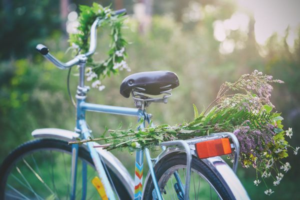 Blomsterkrans på styret till en cykel med en stor blombukett på pakethållaren.