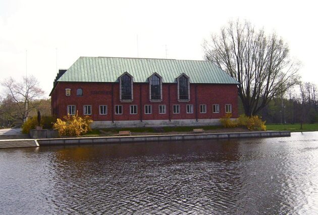 Tegelhus med koppartak, vid vatten.