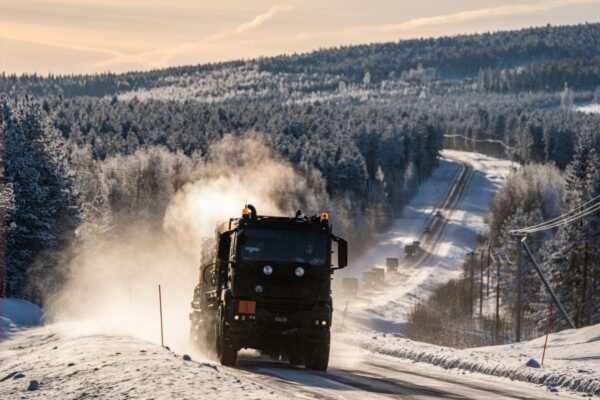 Militära bandvagnar på snöig väg.