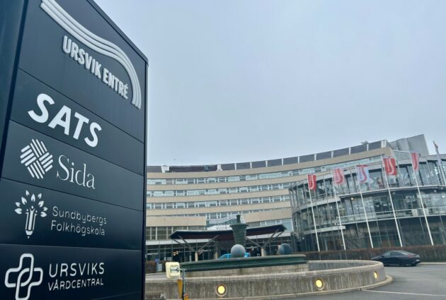 Skylt med företagsnamn framför kontorsbyggnad.