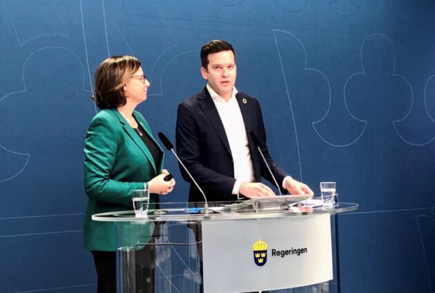Kvinna i dräkt och man i kostym vid podium.